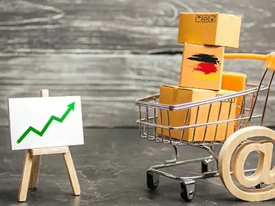 Illustratie voor webinar Online succes in Duitsland: kartonnen pakket met Duitse vlag in winkelwagentje, @-teken en stijgende grafiek. Visualiseert e-commerce groei en succesvolle markttoetreding tot de Duitse markt voor MKB.