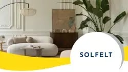 Stijlvolle woonkamer met modern designmeubilair van SOLFELT, lichte sofa, houten kast, kunst en grote groene plant in een elegant interieur; visuele header van Trusted Shops-klantverhaal met SOLFELT-logo.