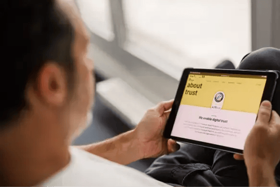 Persoon bekijkt Trusted Shops-website op een tablet. Op het scherm de ‘About trust’-pagina met Trusted Shops-keurmerk en uitleg over digitale betrouwbaarheid. Beeld illustreert online vertrouwen, keurmerken en e‑commerce security.