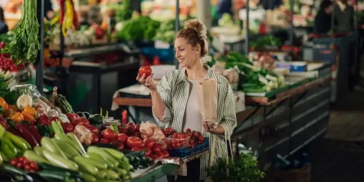 Een vrouw kijkt naar fruit op een markt en overweegt daarmee marktplaats vs webshop