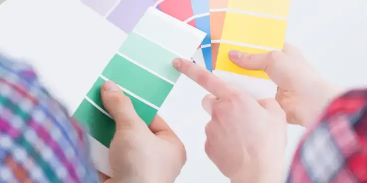 Twee personen vergelijken kleurstalen in verschillende tinten tijdens het optimaliseren van een webshop, als metafoor voor A/B-testen en het kiezen van de beste designoptie.