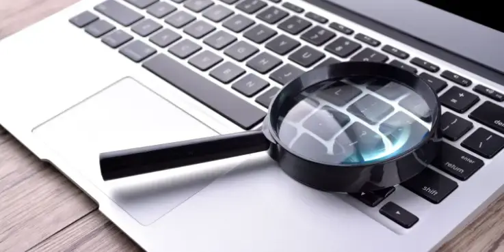 Vergrootglas op een laptoptoetsenbord als symbool voor keyword research en SEO-tools om betere zoekwoorden te vinden en online zichtbaarheid te vergroten.