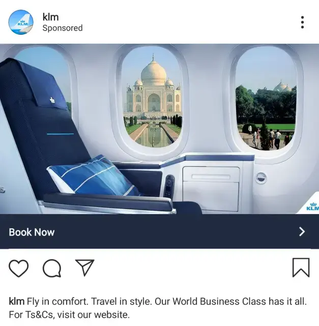 KLM Instagram-advertentie met een World Business Class-stoel in een vliegtuig, met uitzicht op de Taj Mahal door het raam. Luxe vliegervaring, comfortabel reizen en premium service benadrukt.