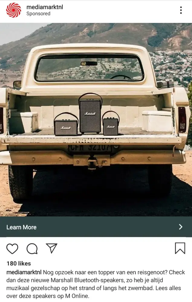Instagram-advertentie van MediaMarkt met drie Marshall Bluetooth-speakers in de laadbak van een beige pick-uptruck in een zonnig berglandschap. Promoot draagbare speakers voor muziek onderweg of op vakantie.