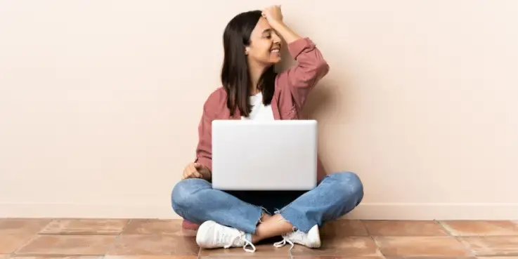 Vrouw met een laptop die op de grond zit, heeft iets gerealiseerd en is van plan de oplossing te zoeken.