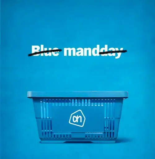 Screenshot van Facebook-post van Albert Heijn over Blue Monday. Blauwe achtergrond met een blauw AH‑winkelmandje en doorgestreepte tekst 'Blue manday'. Caption: 'Zo’n dag kan korter, maar samen maken we ’m draaglijk.' Realtime marketing en merkcommunicatie. 