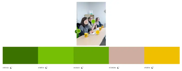 Adobe Color Wheel‑weergave met een foto van een vergadering in het Trusted Shops‑kantoor. De afbeelding toont geselecteerde kleurstalen in groentinten, beige en geel die overeenkomen met elementen in de kantooromgeving.