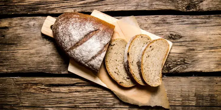 Vers gebakken brood op een houten snijplank met enkele gesneden plakken, symbolische afbeelding voor het begrip ‘breadcrumbs’ in website‑navigatie en SEO‑optimalisatie.