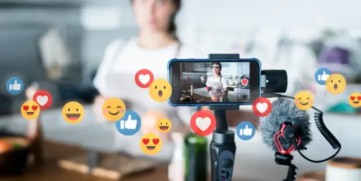 Smartphone op statief filmt een live shopping‑uitzending waarin een presentator producten demonstreert, omringd door likes en emoji‑reacties die de interactie van kijkers tijdens livestream shopping in e‑commerce weergeven.