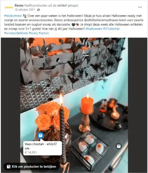 Facebookafbeelding van Xenos met Halloween woondecoratie: zwarte en oranje kaarsen, vleermuisdecoratie aan de muur, glazen schaal met accessoires en een vaas met oranje bloemen. Sfeervolle Halloween styling voor huisdecoratie en feestdagen.