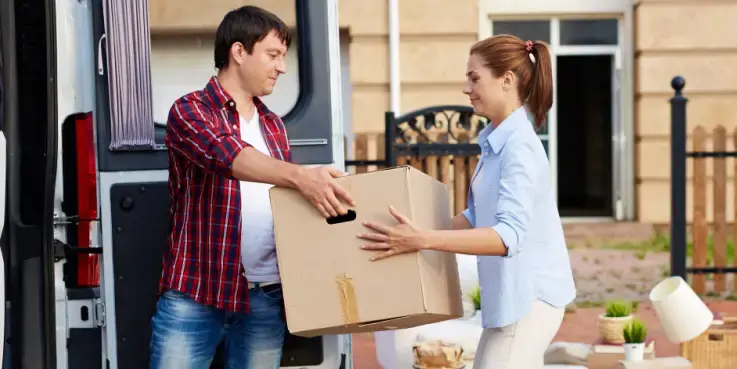 Mensen die een verhuisdoos uit een bus tillen, als metafoor voor het veilig verhuizen van een website naar een nieuw domein met behoud van SEO-waarde.