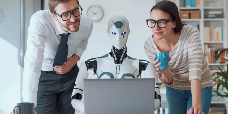 Een foto van een humanoid robot die achter een laptop zit en een man en een vrouw kijken over de schouders mee. AI helpt met producten zoeken