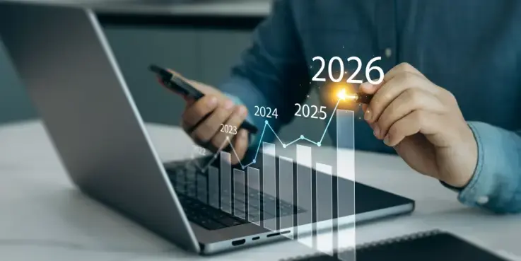 Een man zit achter een laptop met een grafiek die omhoog gaat, voor toekomstige groei van bedrijfsactiviteiten in 2026. Nieuwe kansen, uitdagingen en strategieën in de trends voor 2026